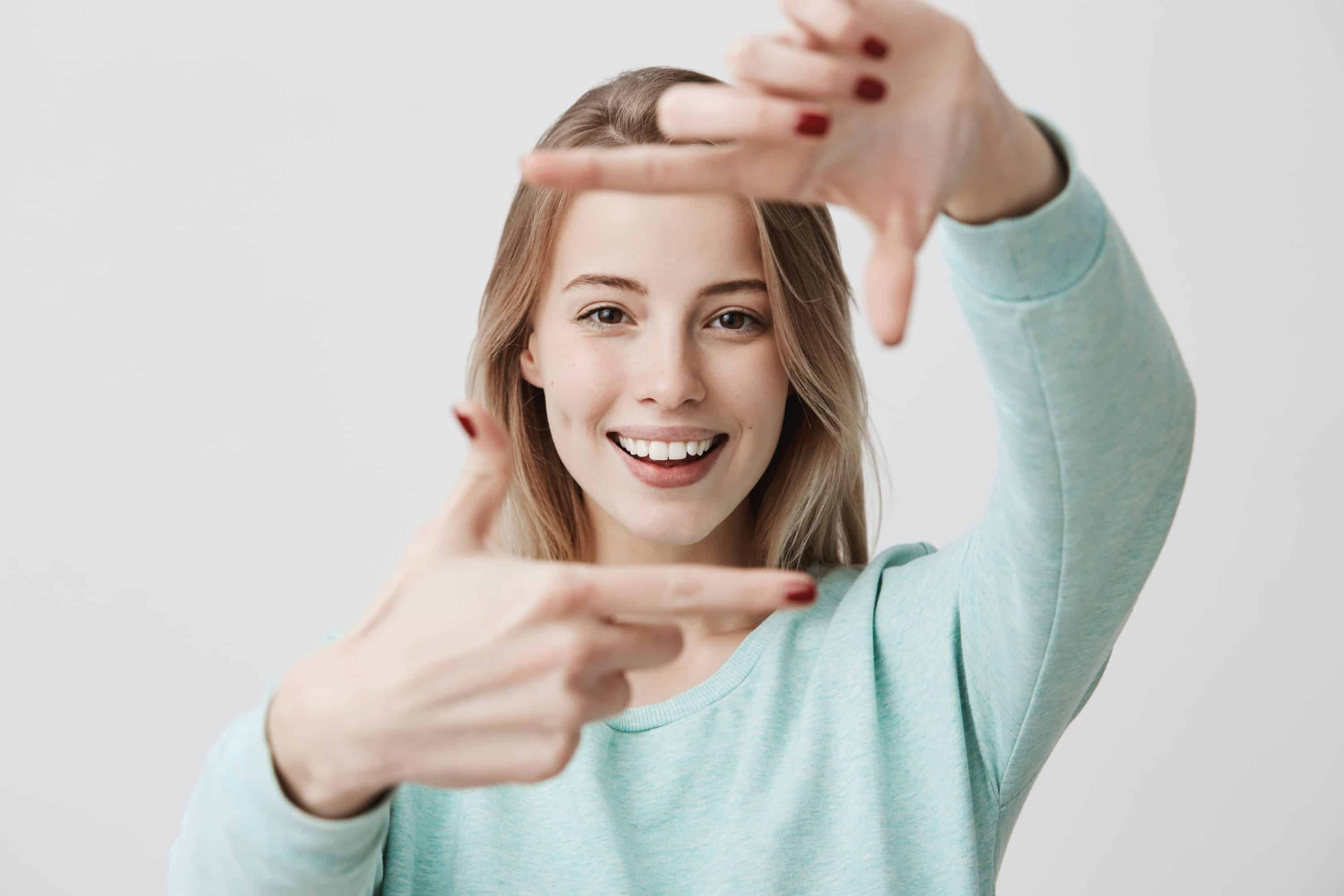 portrait young blonde woman making frame gesture with hands scaled